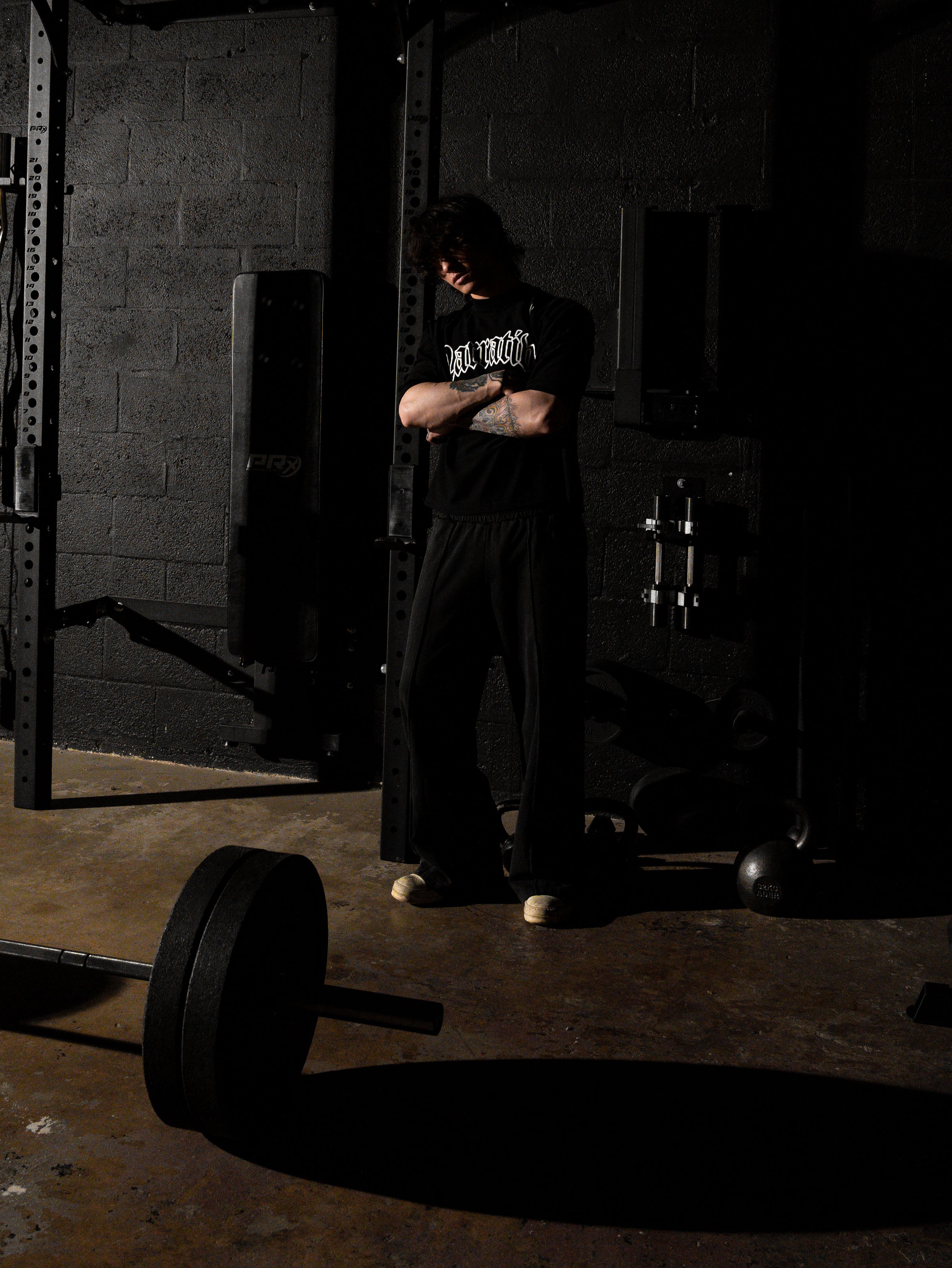 Person standing in a dark gym with weights on the floor