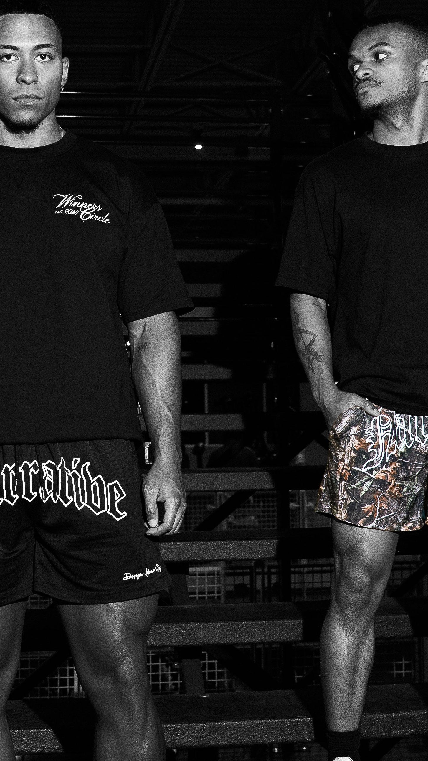 Two men wearing Narrative black t-shirts and Narrative shorts standing on a staircase.